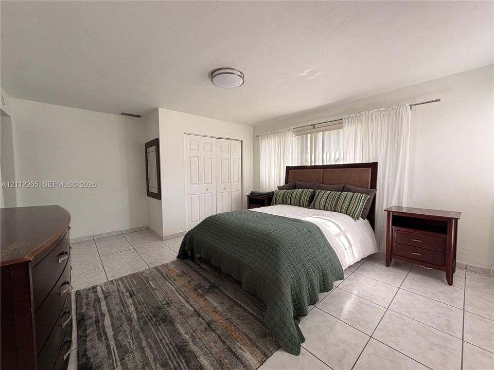 Room featuring neutral wall finishes, tile flooring, built-in dual-door closet, and a flush-mount ceiling light fixture