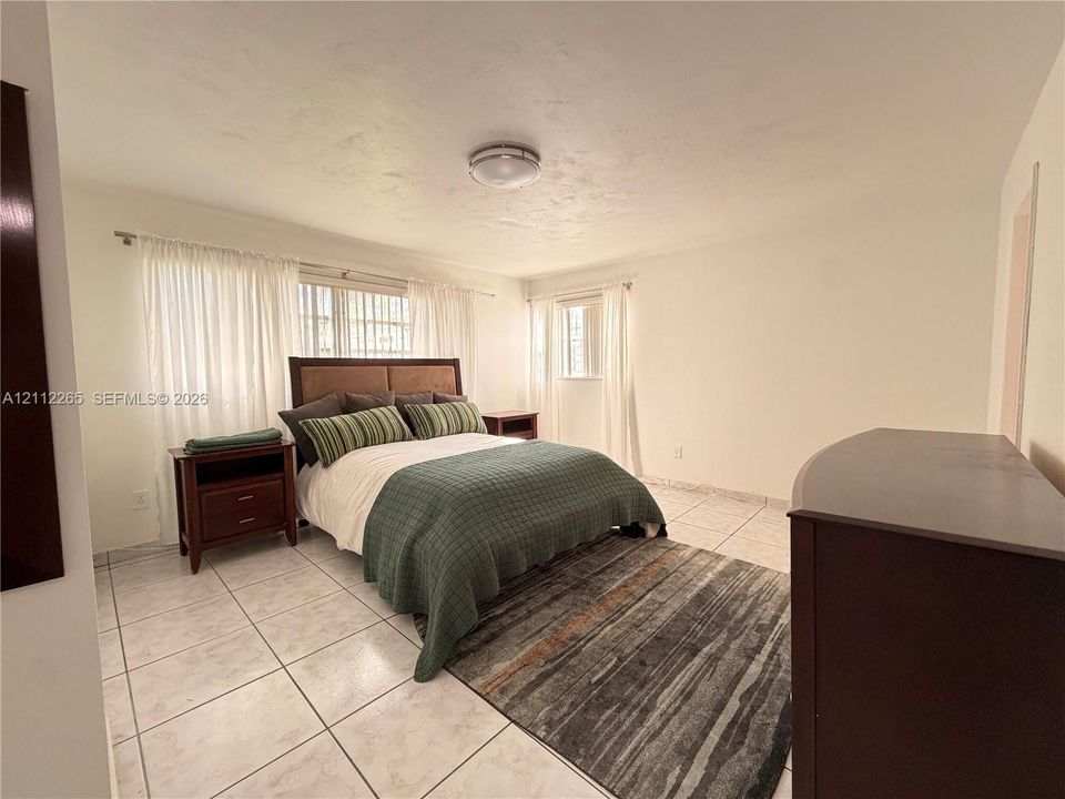 Spacious room featuring neutral wall tones, large-format tile flooring, and multiple windows providing natural light