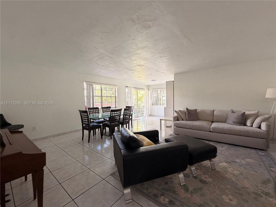 Open-concept room featuring light-toned tile flooring, textured ceiling finish, and dual sliding glass doors