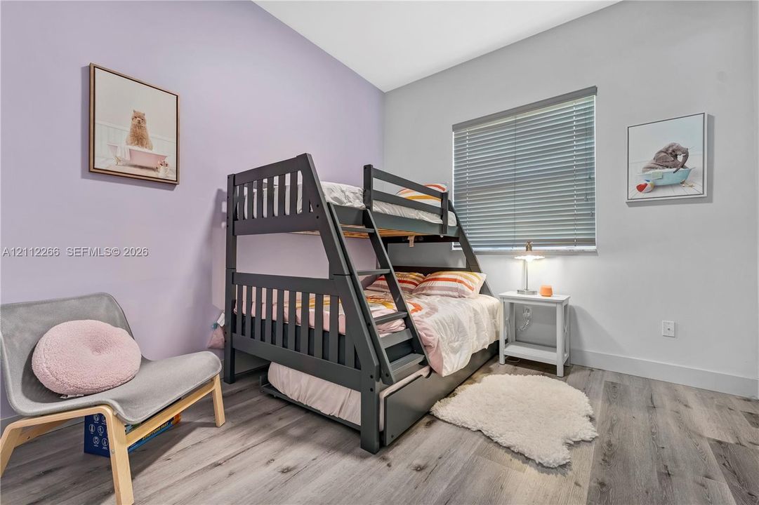 Bedroom featuring wood-finish flooring, high ceilings, and a horizontal window with adjustable blinds