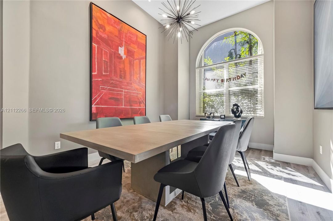 High-ceiling room featuring wood-finish flooring, a prominent arched window, and a multi-arm sputnik-style chandelier