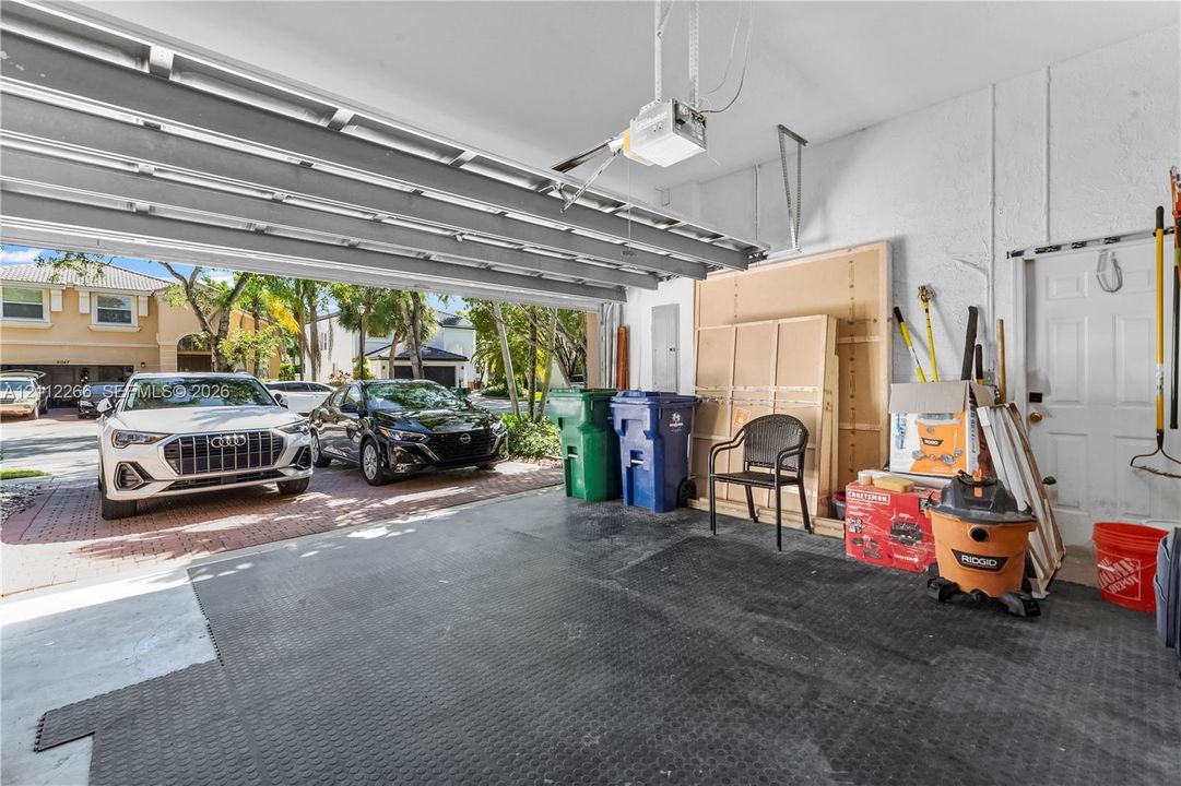 Two-car garage featuring a motorized overhead door, durable flooring, integrated ceiling-mounted door opener, and a dedicated pedestrian access door