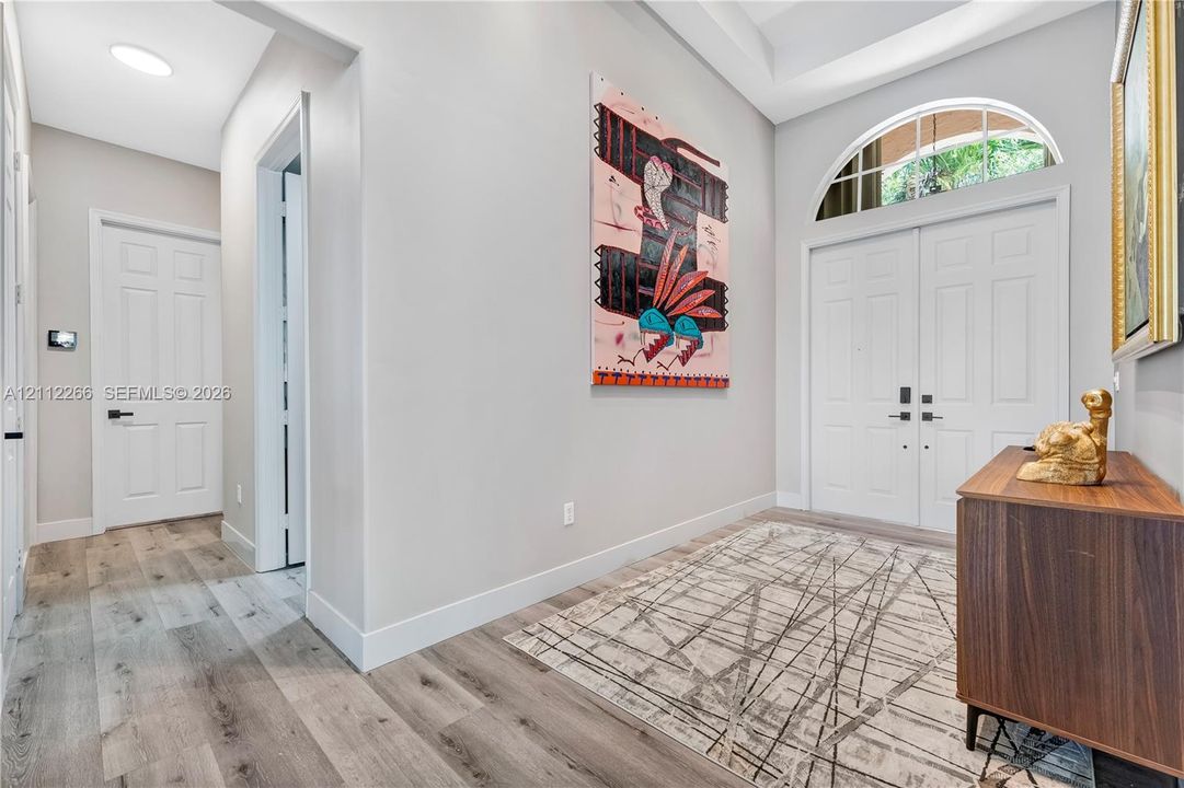 Foyer featuring double-door entry with arched transom window, high ceilings, and wood-finish flooring