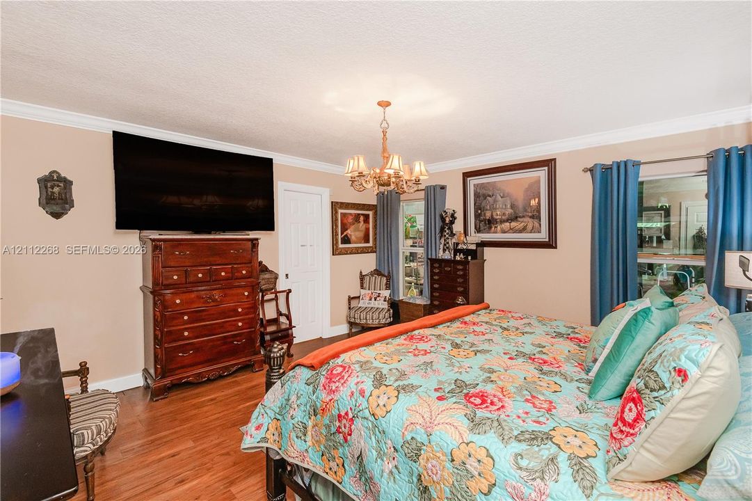 Wood-finish flooring, multi-arm metal chandelier, and crown molding