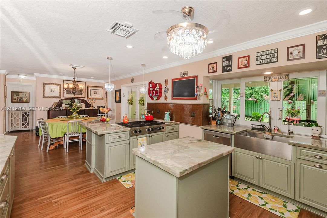 Kitchen featuring a large central island, custom cabinetry, a professional-style gas range, farmhouse-style sink, and stone-finish countertops