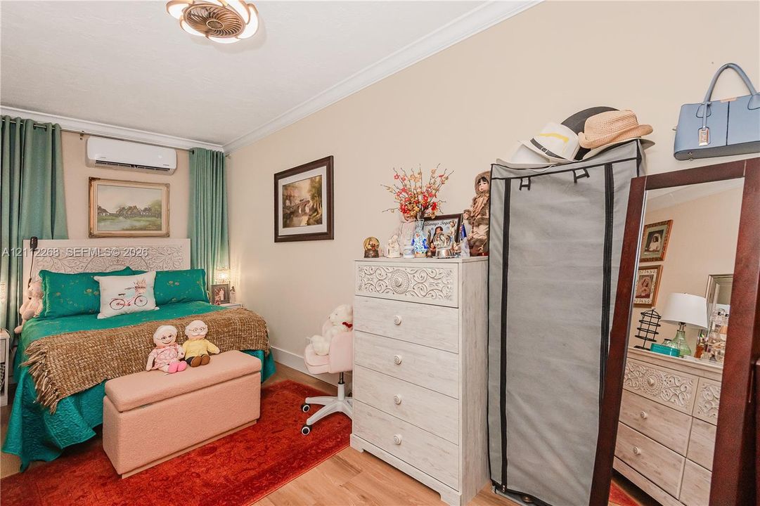 Interior space featuring crown molding, wood-finish flooring, a wall-mounted ductless climate control unit, and a decorative semi-flush mount ceiling fixture