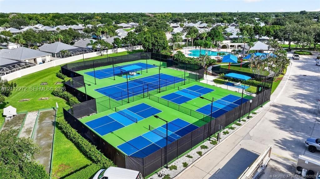 Recreational area featuring multiple fenced tennis and pickleball courts, a swimming pool, and dedicated shade structures