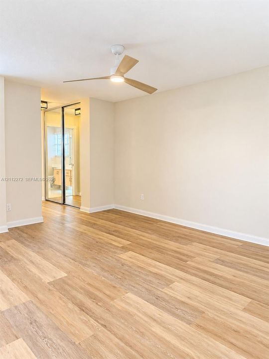 Interior space featuring wood-finish flooring, a contemporary three-blade ceiling fan with integrated lighting, and mirrored closet doors