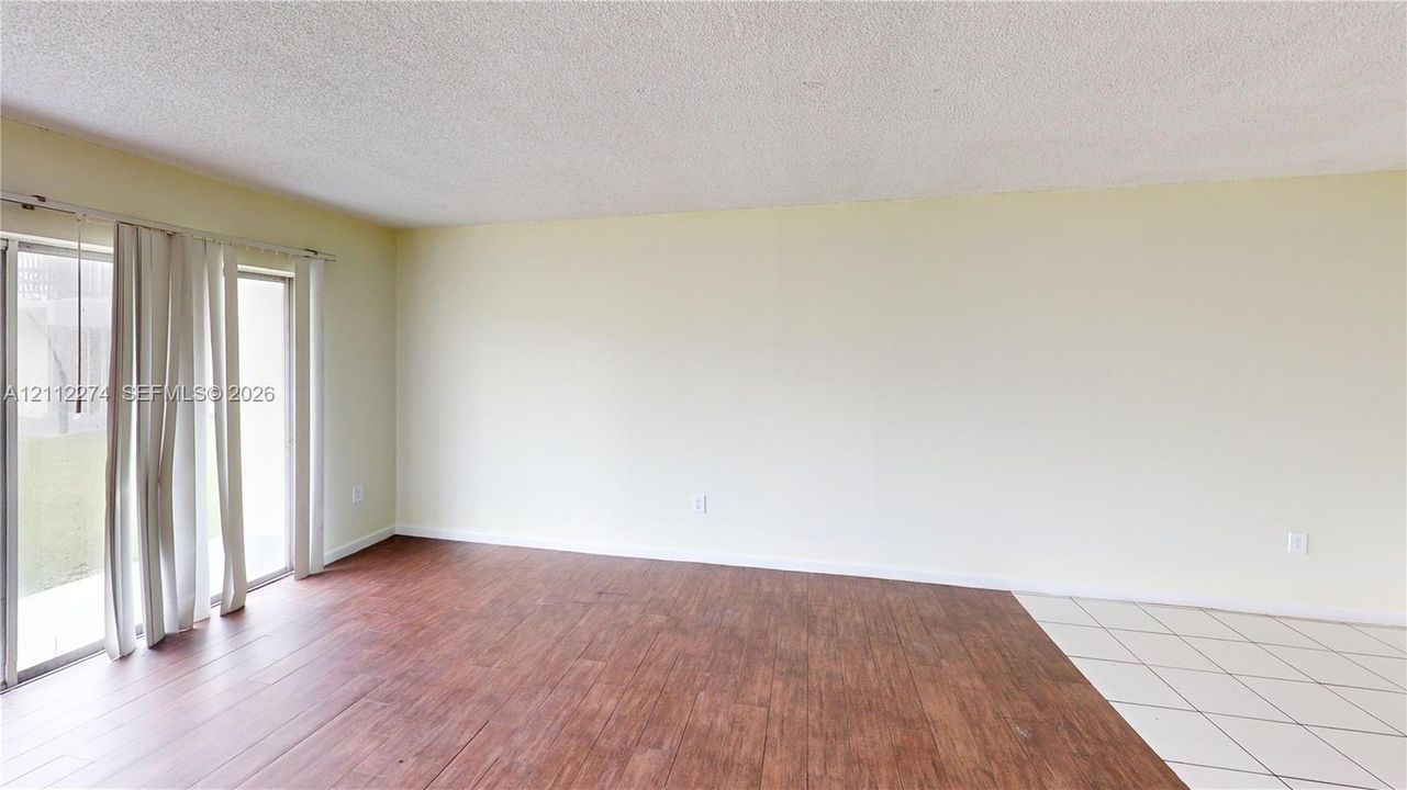 Interior room featuring wood-finish flooring, white tile flooring, and large sliding glass doors