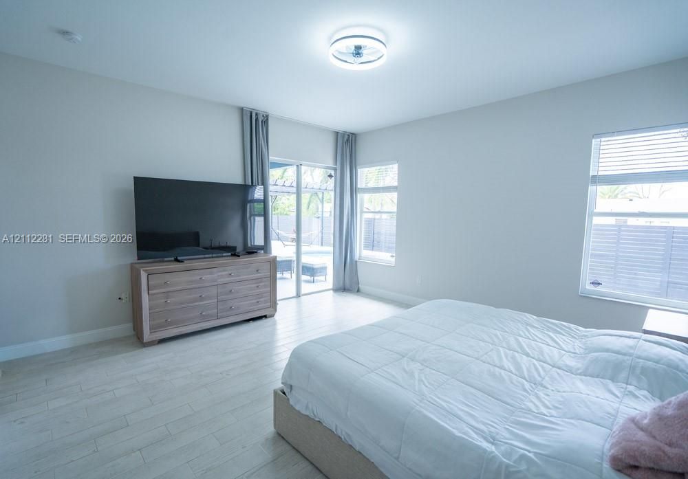 Neutral-toned room featuring light wood-finish flooring, recessed lighting, and sliding glass doors