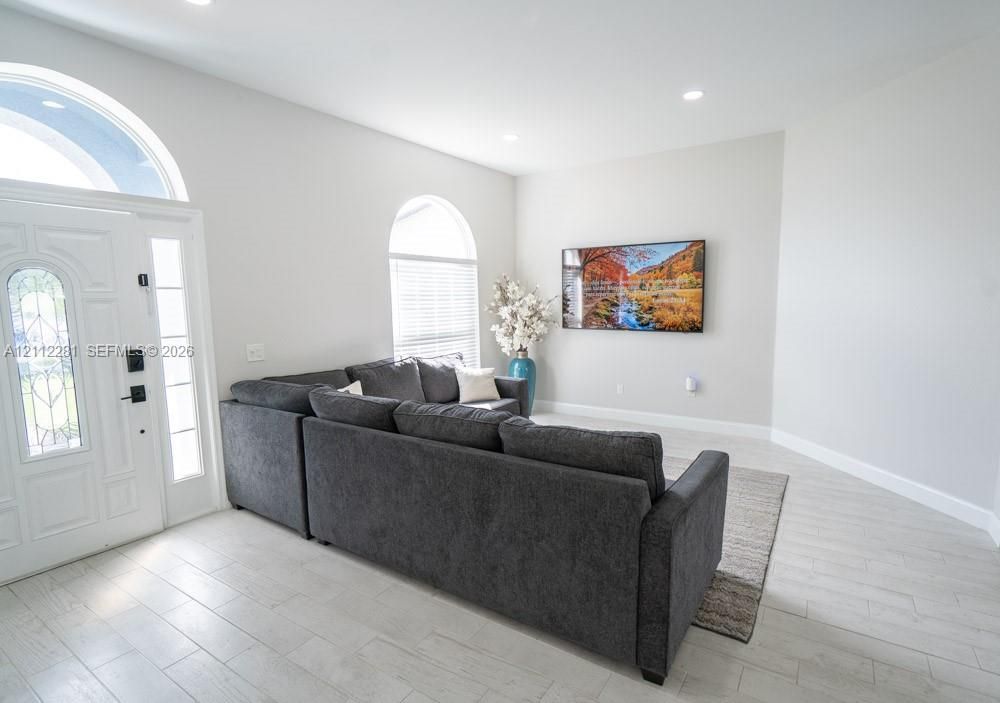 Entryway featuring high ceilings, arched windows, recessed lighting, and light-toned tile flooring