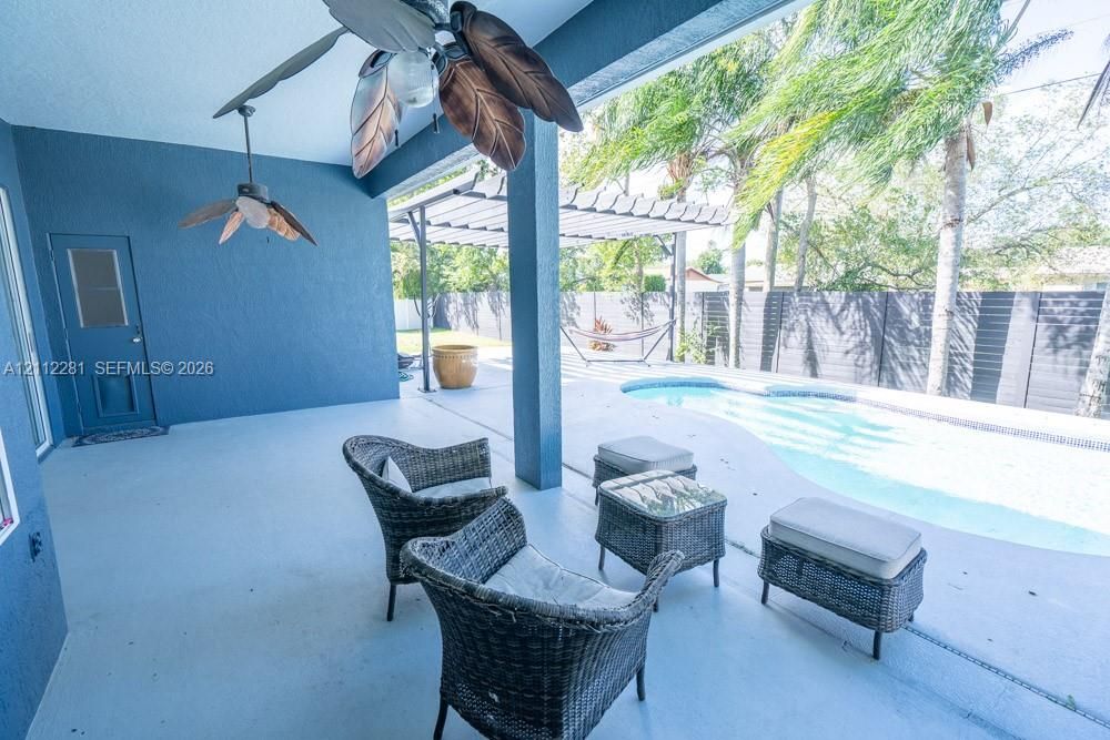 Covered patio featuring two ceiling fans, in-ground swimming pool, horizontal slat privacy fencing, and a pergola-covered patio area