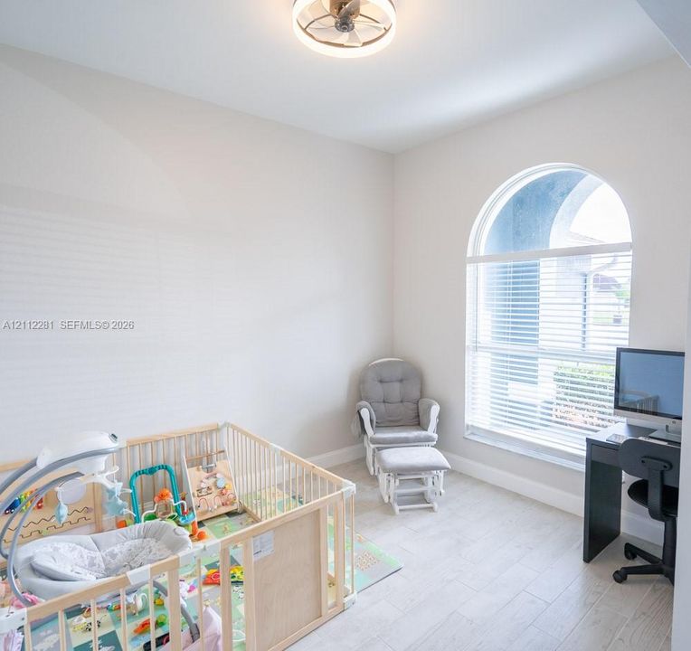 Arched window with light-toned wood-finish flooring and integrated circular ceiling fan fixture