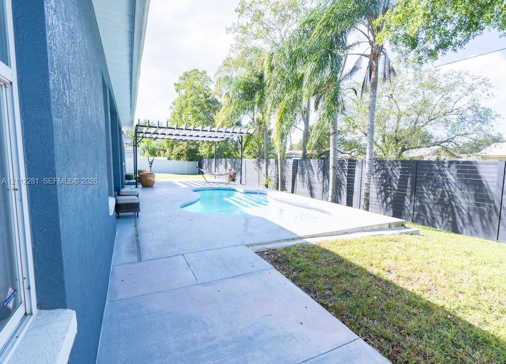 Backyard featuring an in-ground pool, concrete patio, pergola, and horizontal-slat perimeter fencing