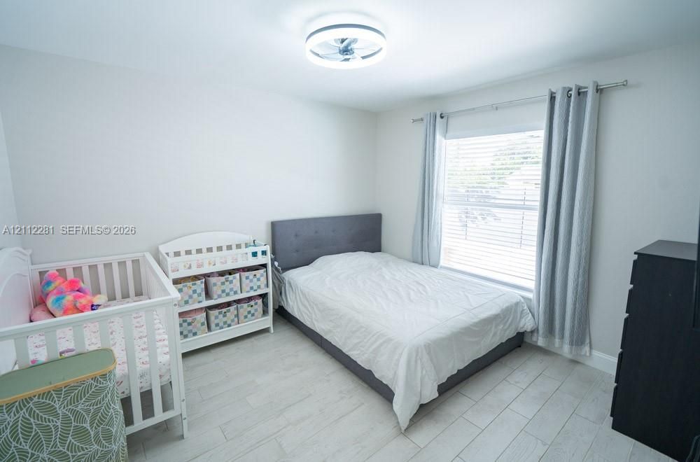 Neutral-toned interior featuring wood-finish tile flooring, a recessed ceiling fan light fixture, and horizontal window blinds