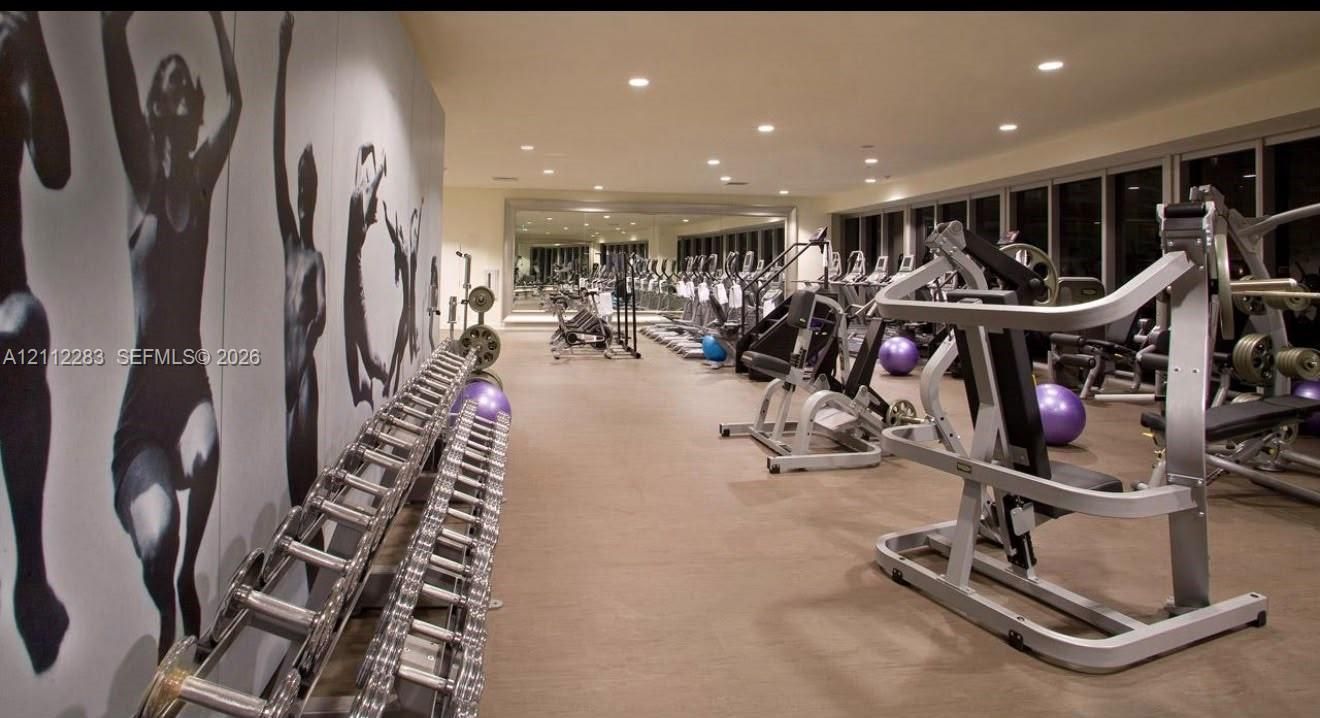 Fitness space featuring floor-to-ceiling windows, full-length wall mirrors, and recessed lighting