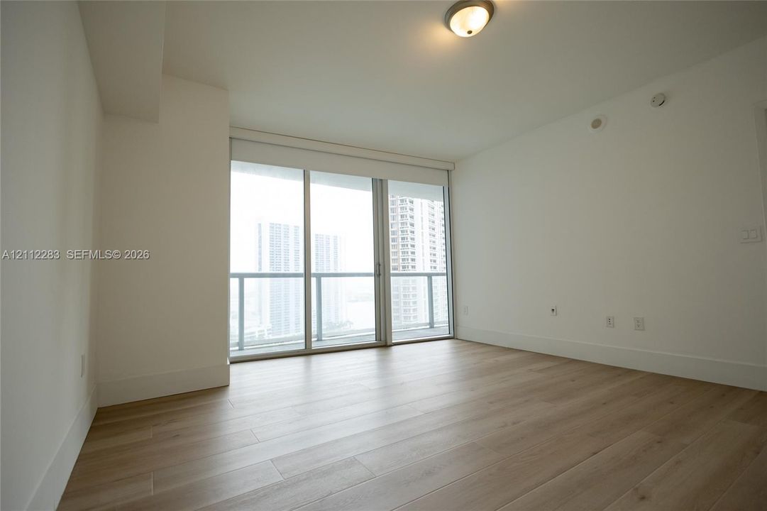 Interior space featuring light-toned wood-finish flooring, floor-to-ceiling glass sliding doors, and a flush-mount dome light fixture