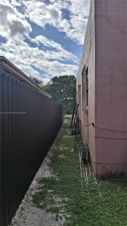 Side yard exterior featuring a vertical metal privacy fence and smooth stucco wall finish