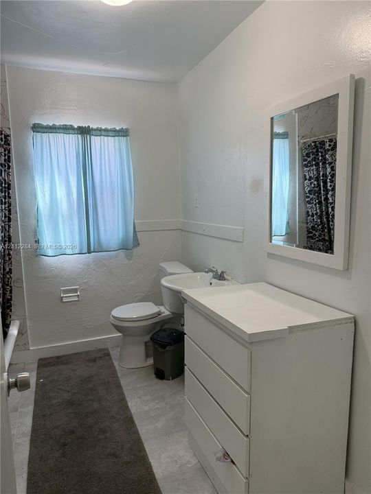 Bathroom featuring a white multi-drawer vanity, a wall-mounted rectangular mirror, and textured wall finish