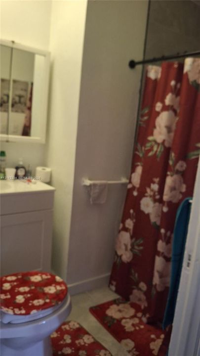 Bathroom featuring a white vanity cabinet, mirrored medicine cabinet, wall-mounted towel bar, and a shower area with a curtain rod