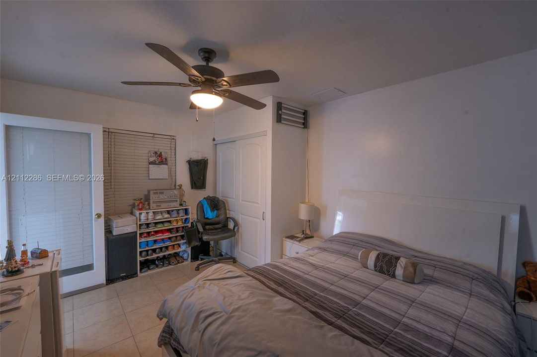 Ceramic tile flooring, ceiling fan with integrated light fixture, dual-panel closet doors, and glass-paneled exterior door