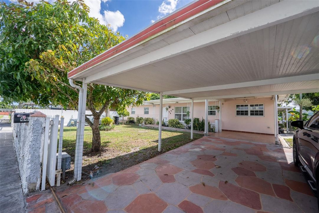 Covered carport featuring flagstone paving, integrated outdoor lighting, and a mature tree-lined front yard