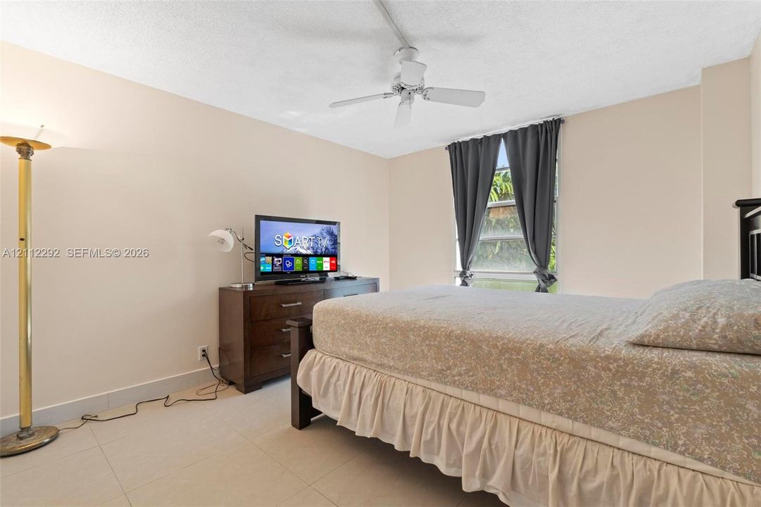 Room featuring light-toned neutral walls, polished tile flooring, and a ceiling-mounted fan
