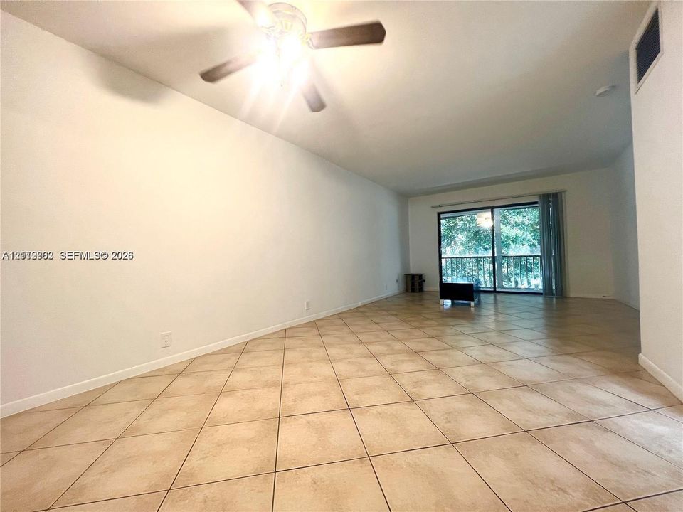 Interior space featuring neutral tile flooring, a ceiling fan with integrated lighting, and a sliding glass door providing natural light
