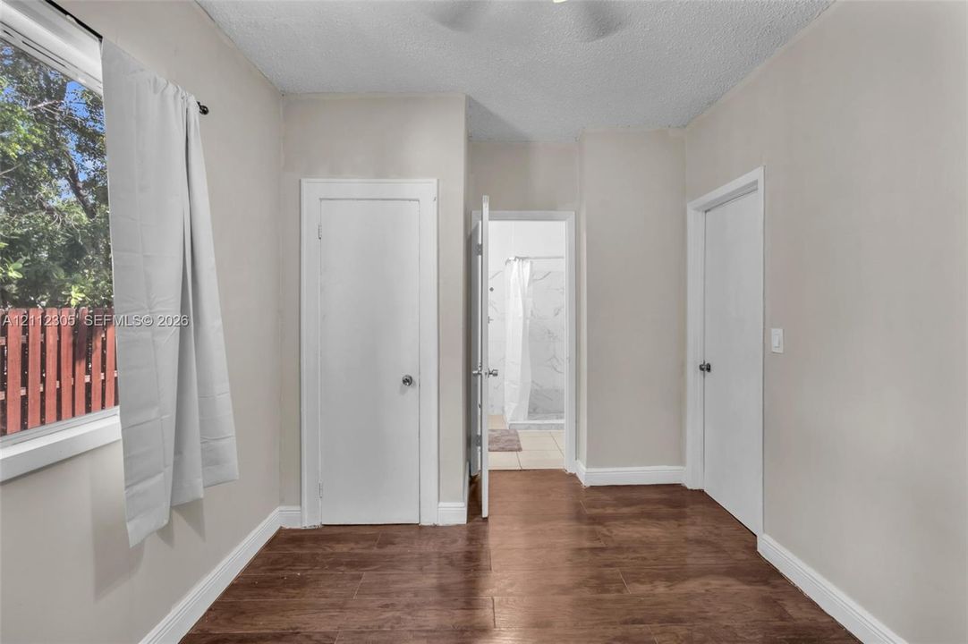 Wood-finish flooring, neutral wall tones, and interior doors with brushed metal hardware