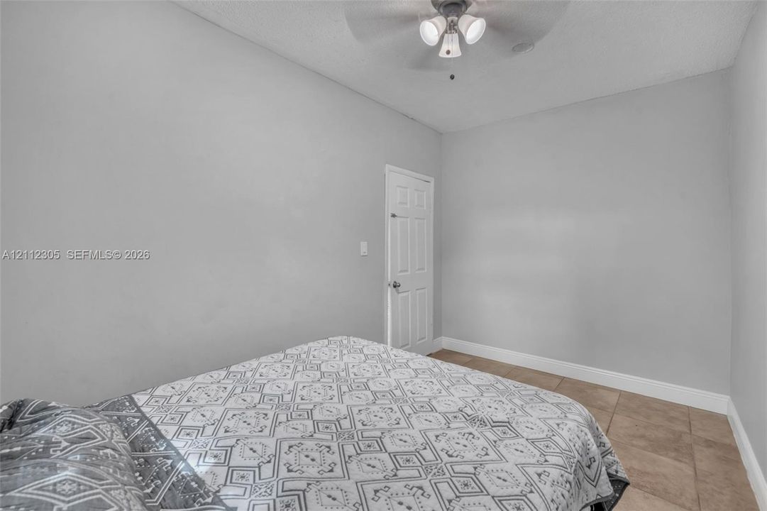 Interior space featuring neutral-toned wall paint, tile flooring, and a multi-light ceiling fan
