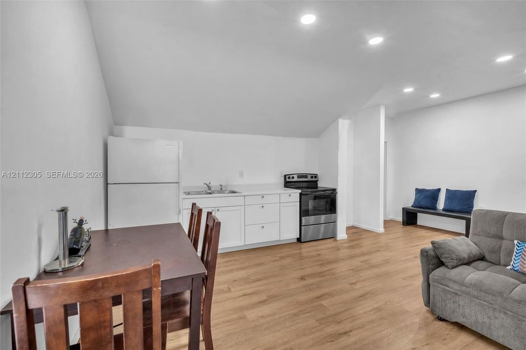 Kitchenette featuring white cabinetry, a solid-surface countertop, stainless steel appliances, recessed lighting, and wood-finish flooring