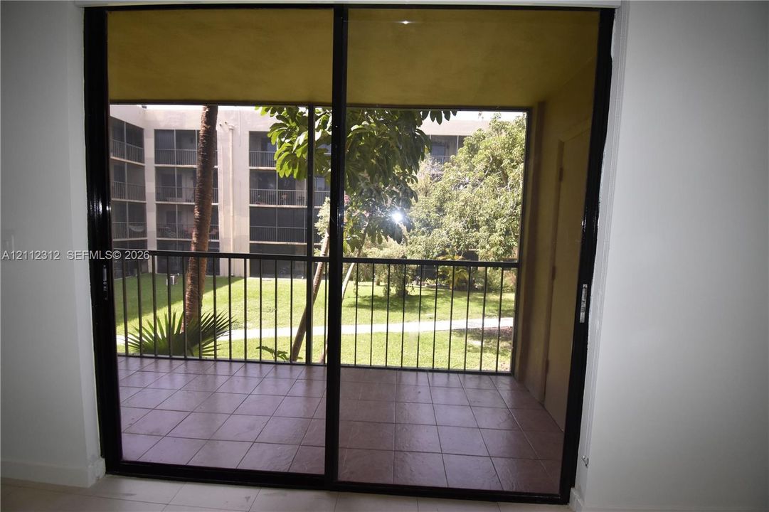 Screened-in balcony featuring tile flooring and a black metal railing