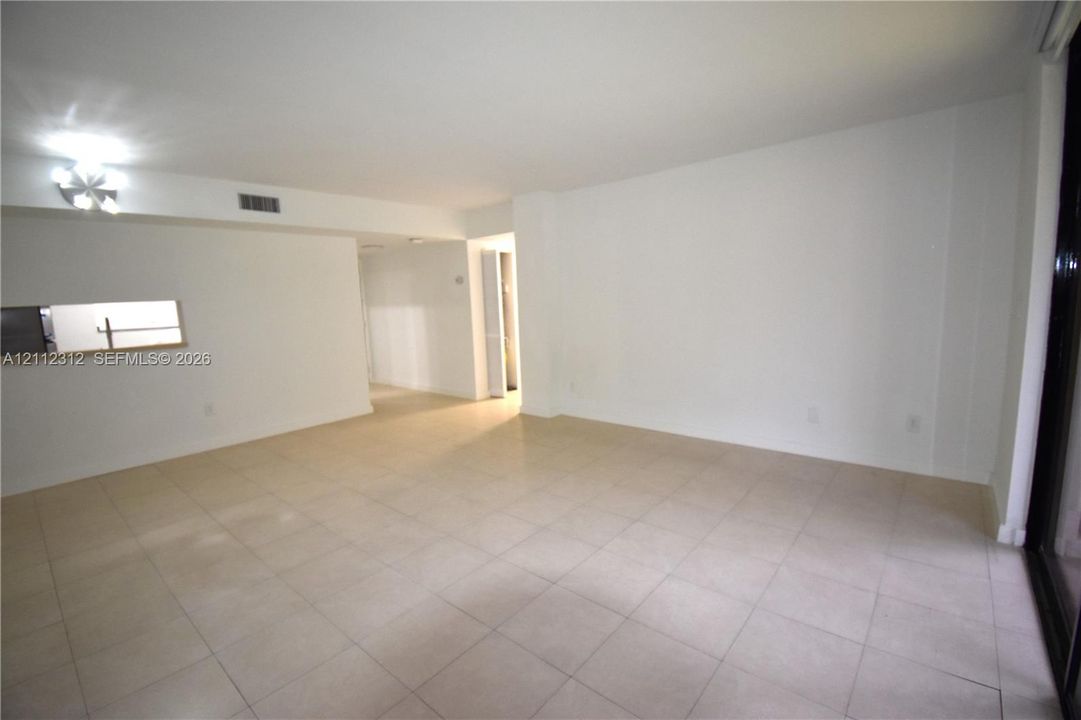 Open-concept interior featuring light-toned tile flooring, recessed ceiling light fixtures, and a pass-through opening