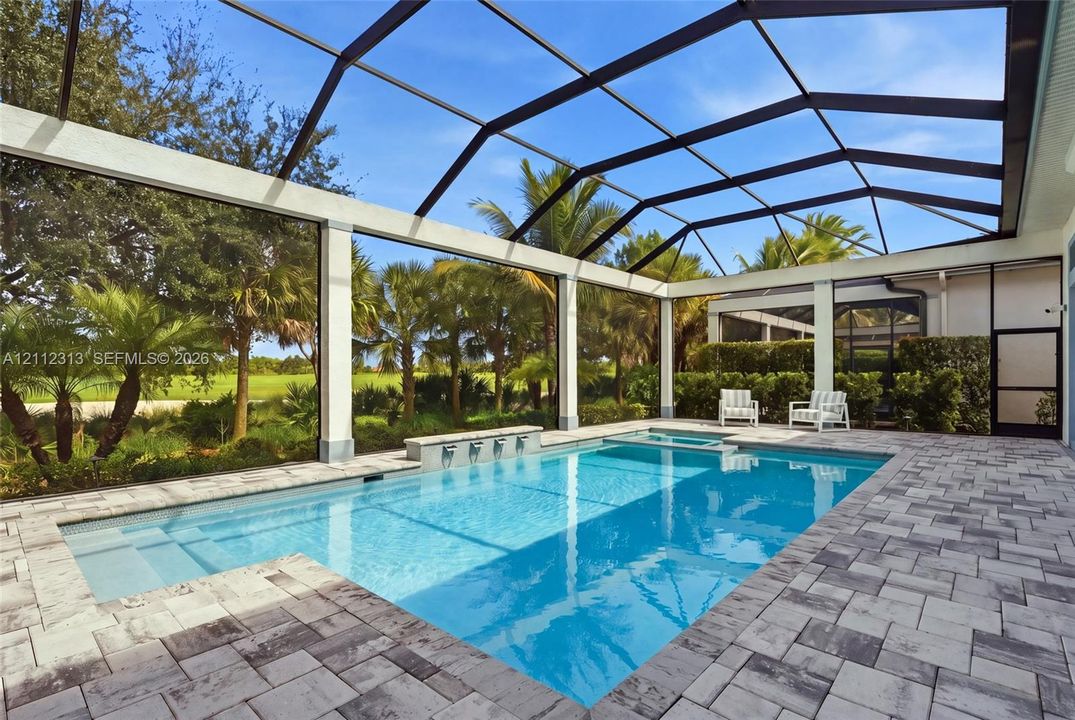 Screened pool enclosure featuring a stone-paver deck, built-in spa, and a wall fountain with multiple spillway spouts