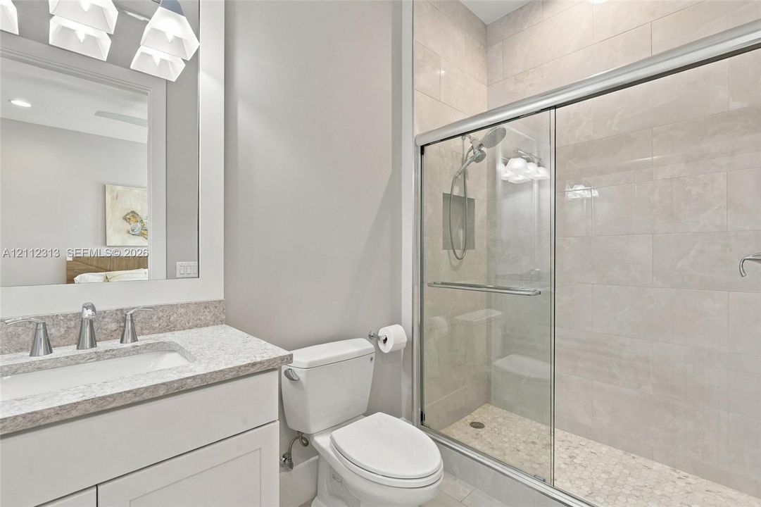 Bathroom featuring a vanity with a light-toned countertop, a frameless glass-enclosed shower with tiled walls and a built-in recessed niche, and polished chrome fixtures