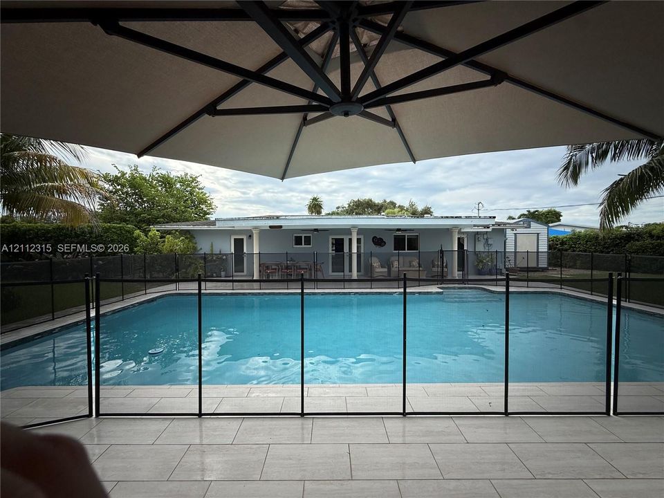 Rear patio featuring tile flooring and an in-ground swimming pool enclosed by black perimeter fencing