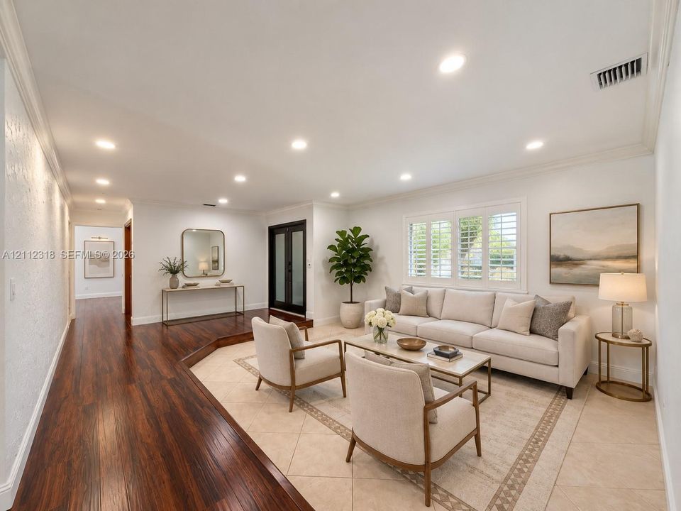 Living area featuring wood-finish flooring, a sunken sitting area with neutral tile flooring, recessed lighting, and windows with interior shutters