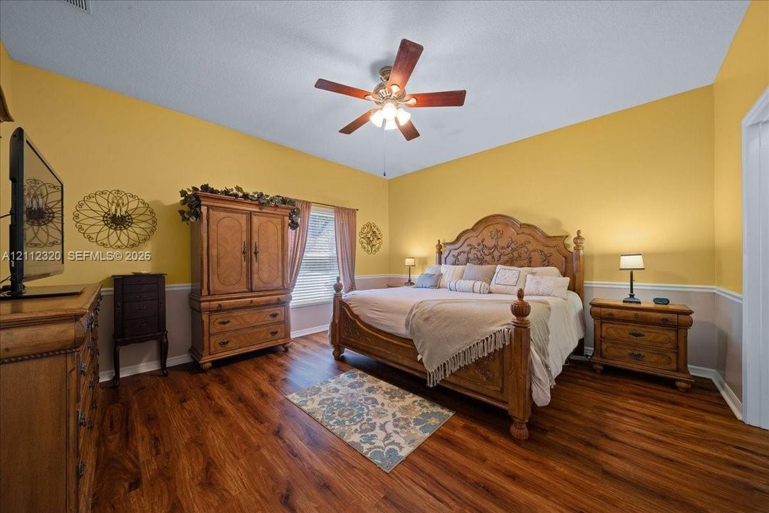 Bedroom featuring wood-finish flooring, two-tone wall treatment, and a ceiling fan with integrated lighting