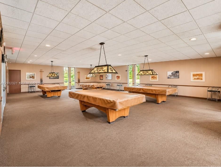 Spacious recreation area featuring a drop ceiling, wall-to-wall carpeting, recessed lighting, and built-in drop-pendant lighting fixtures