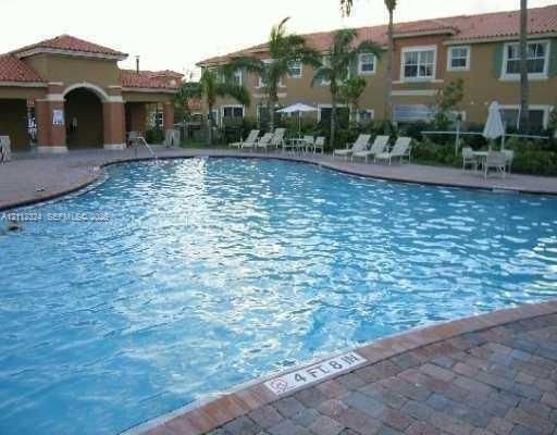 Swimming pool featuring paver decking, arched portico, and palm trees