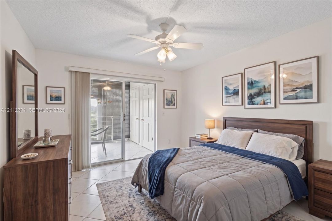 Neutral-toned tile flooring, white ceiling fan with integrated lighting, and glass sliding doors providing exterior access