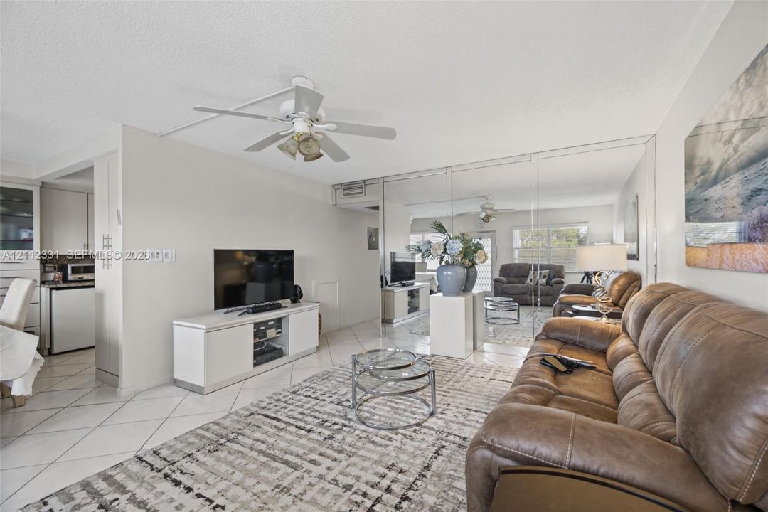 Open-concept interior featuring large-format diagonal tile flooring, a ceiling fan with integrated lighting, and a full-wall mirrored accent