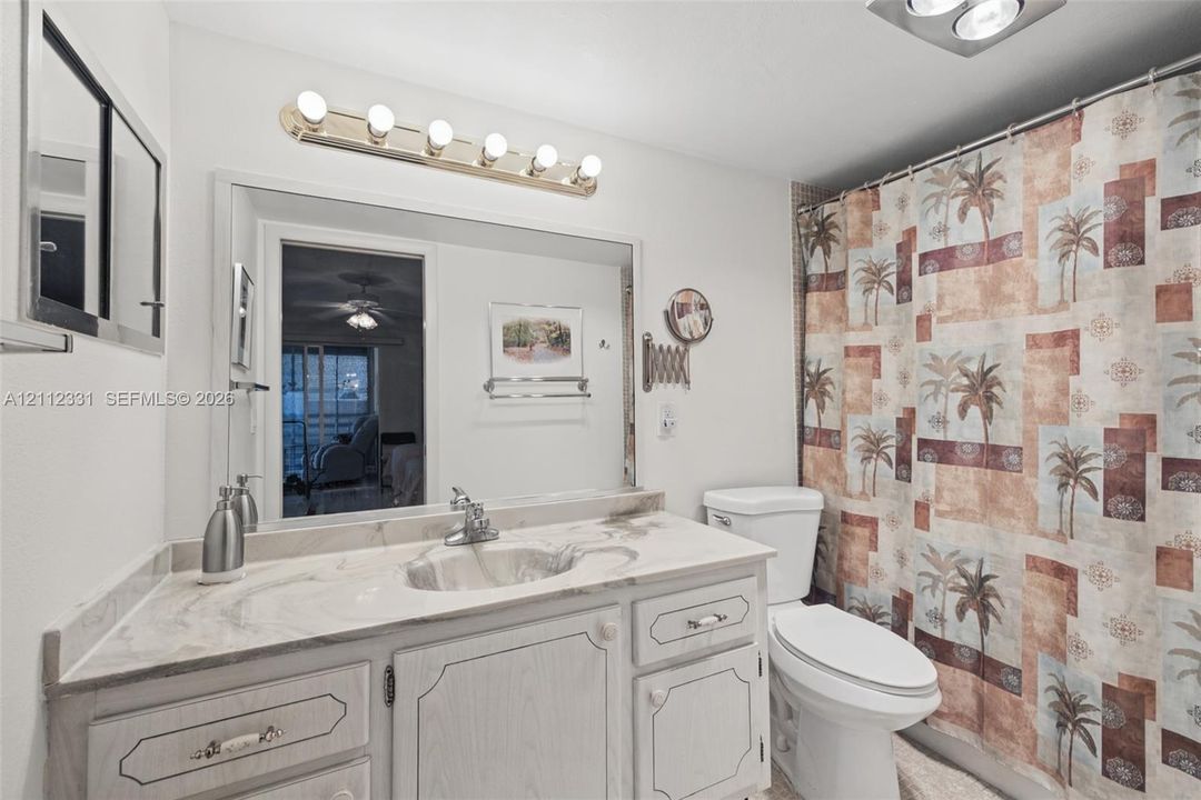 Bathroom featuring a vanity with integrated sink and countertop, large wall-mounted mirror, multi-bulb vanity light fixture, and two-piece toilet