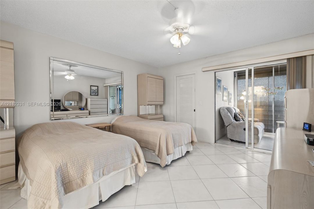 Tile flooring, large wall-mounted mirror, ceiling fan with integrated lighting, and sliding glass door with exterior balcony access