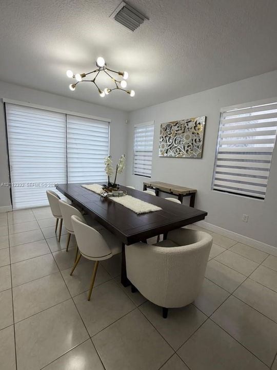 Large-format tile flooring, multi-light sputnik-style chandelier, and retractable dual-layered window shades