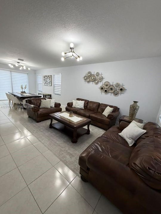 Large-format tile flooring, multi-arm structural chandeliers, and tiered window treatments
