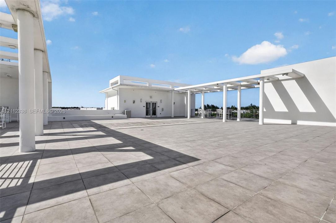 Expansive rooftop terrace featuring large-format tile flooring and multiple structural pergolas supported by cylindrical columns