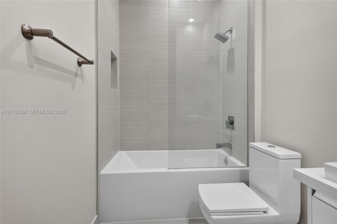Full-height tile surround with a recessed niche, frameless glass shower panel, and wall-mounted shower fixture