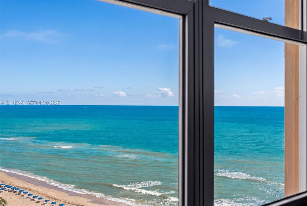 Dark-framed casement window with an expansive ocean horizon and coastline exterior