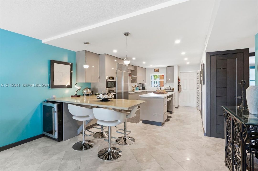 Kitchen featuring high-gloss cabinetry, stone countertops, a central island, recessed lighting, and tile flooring